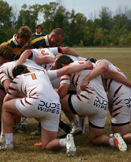 RIT forwards in tiger-striped jerseys bound together in a scrum